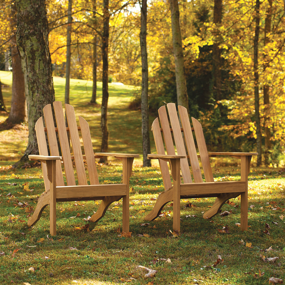 Oxford Garden Oxford Teak Adirondack Chair shown in an outdoor setting
