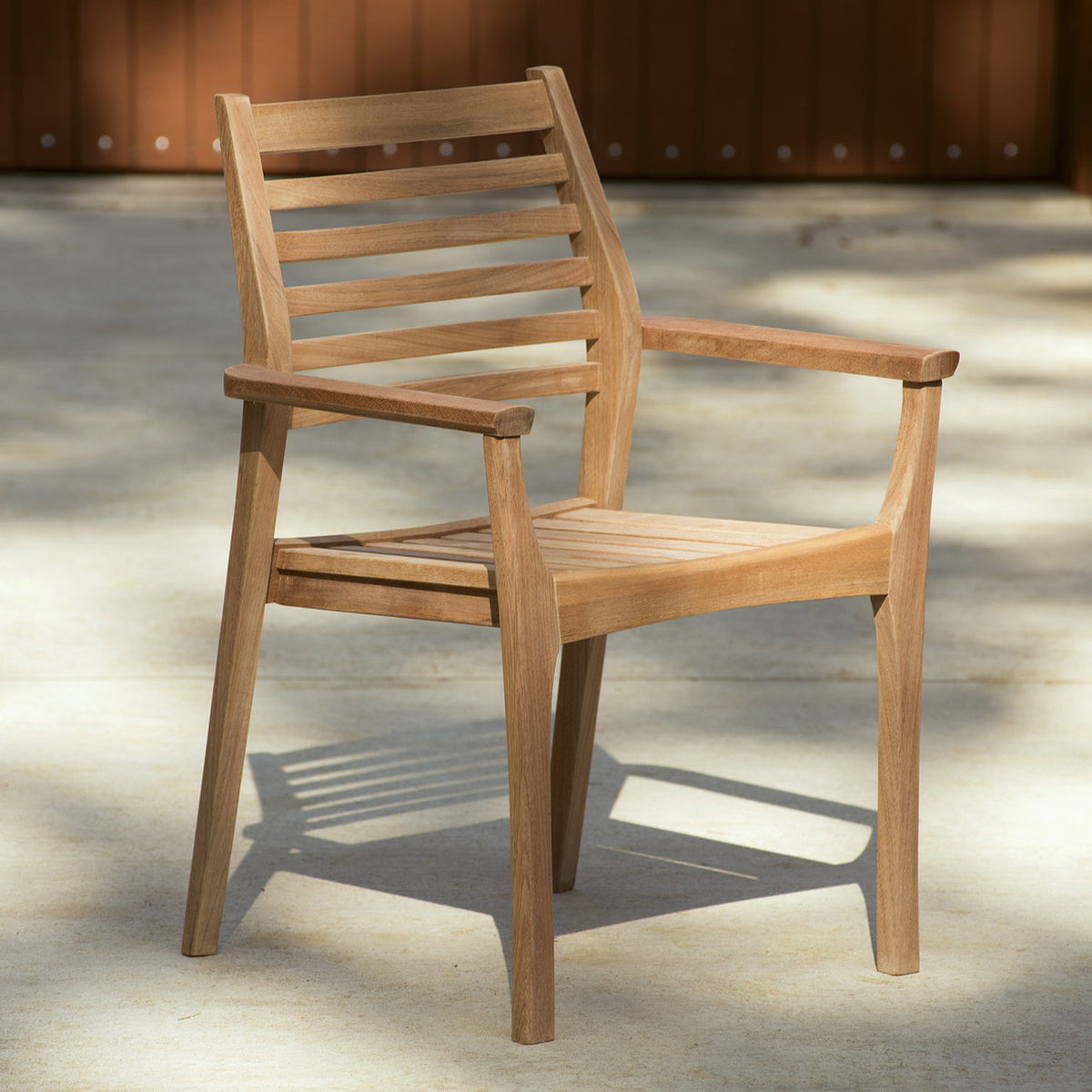 Oxford Garden Mera Teak Stacking Armchair shown in an outdoor setting
