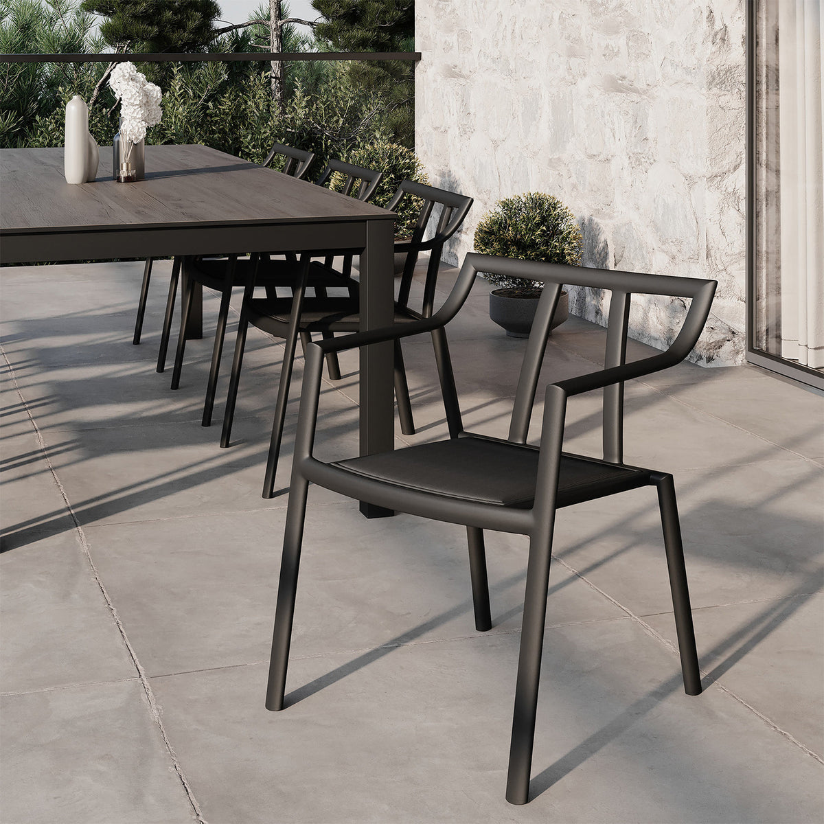 A set table surrounded by open frame sling dining chairs outdoors