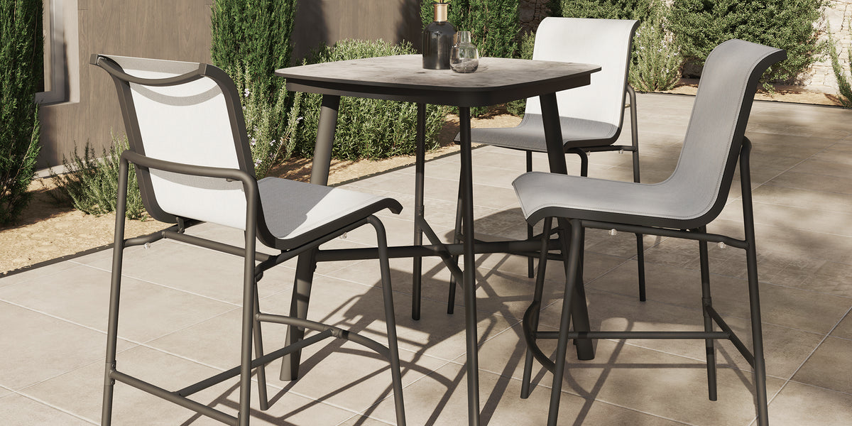 Orso sling bar chairs pulled up to an outdoor bar height table on a terrace