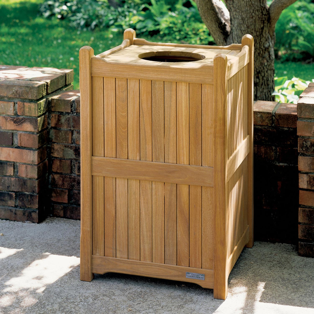 The teak trash receptacle in use on an outdoor terrace beside seating