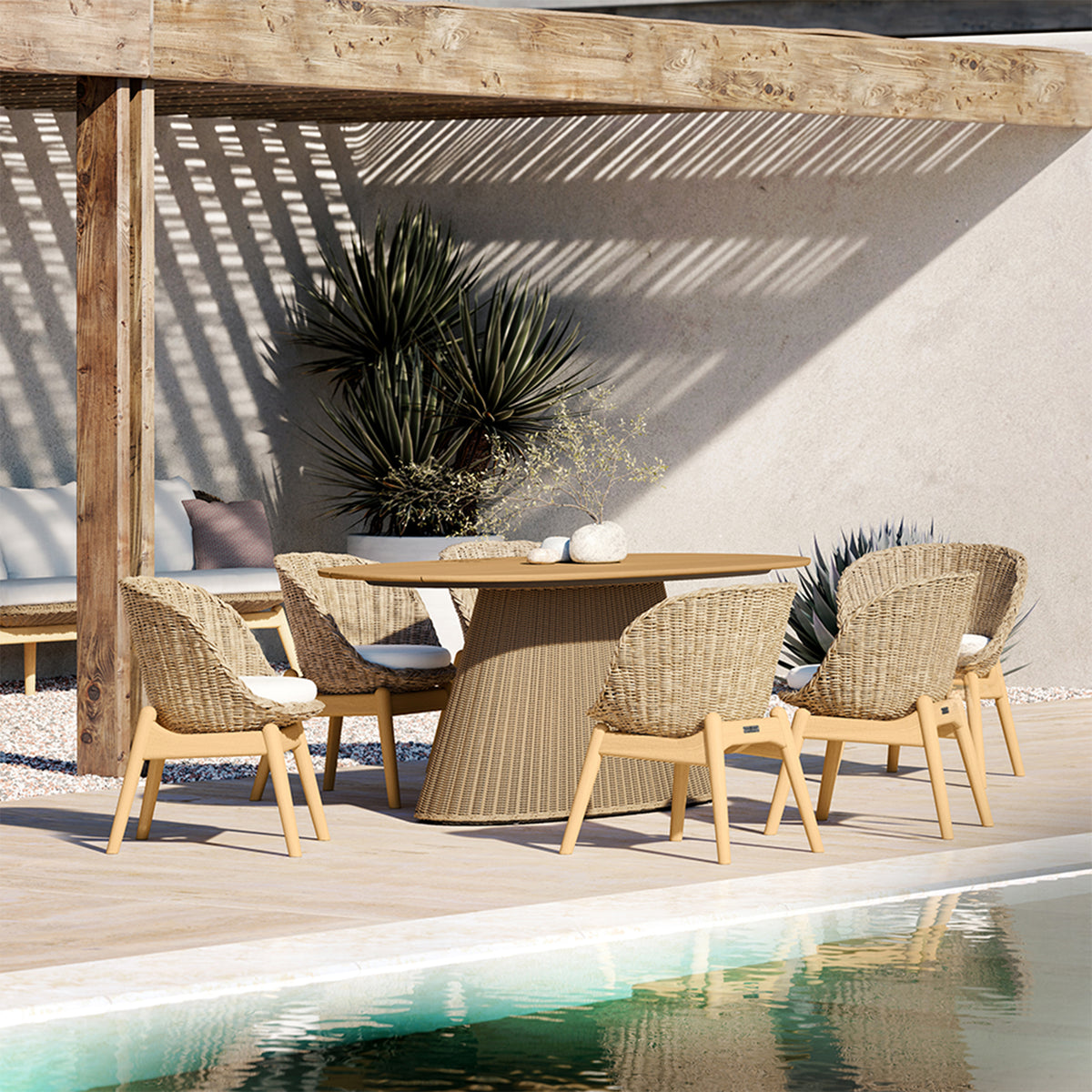Oval dining table on a woven trestle base set with chairs on a terrace