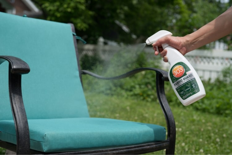 Spraying 303 Fabric Guard onto a patio chair cushion