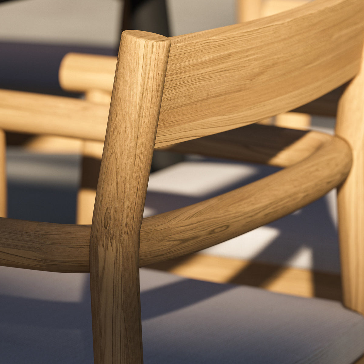 Close view of a Lido teak dining chair with its thin seat pad in place