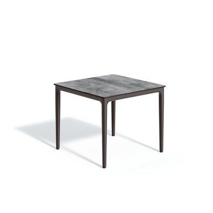 Square outdoor dining table with a pale laminate top on a slim dark aluminum frame, on a plain white background
