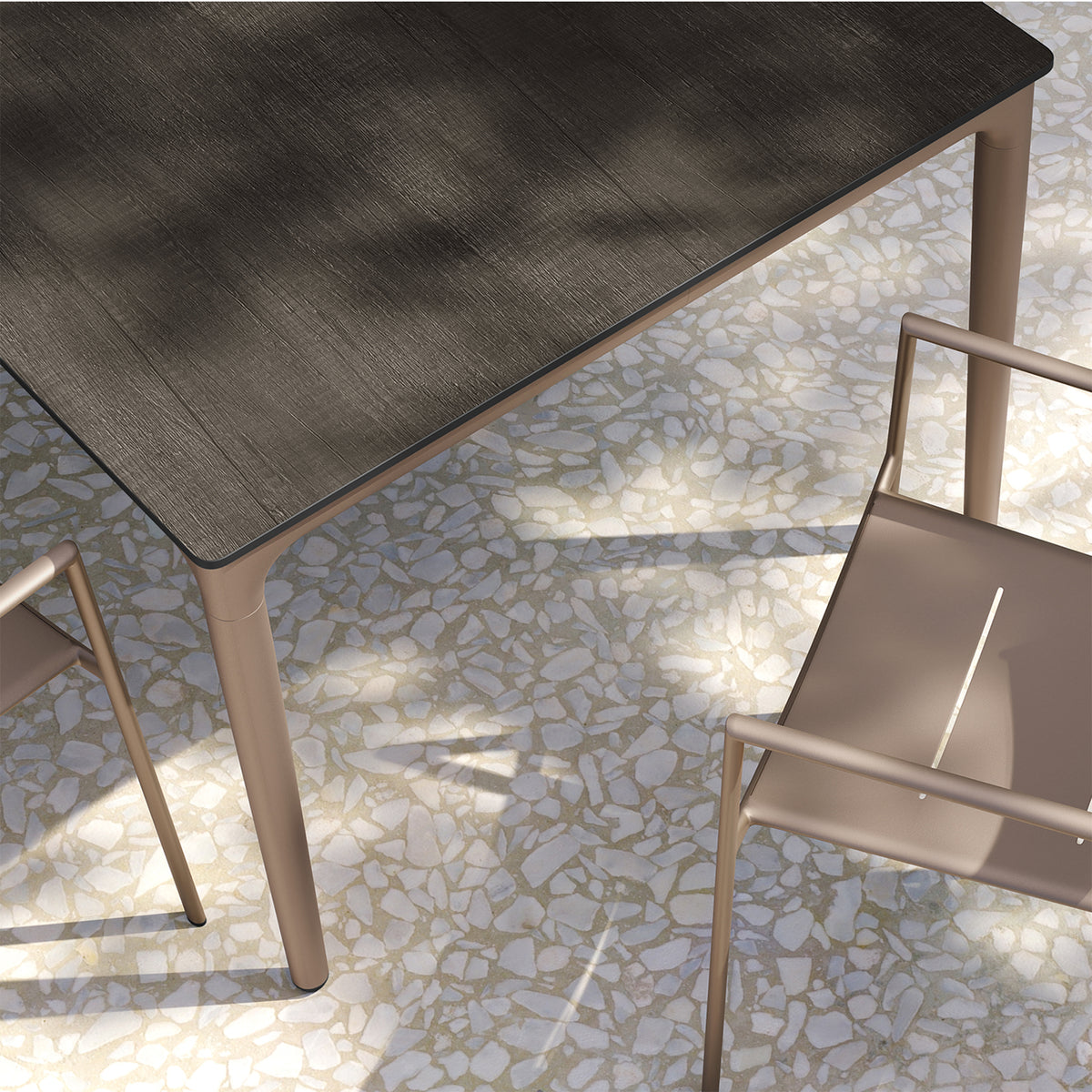 Close view of the corner of the long dining table showing the laminate top edge meeting the aluminum leg