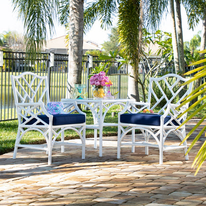 Chippendale outdoor end table styled with flowers between two armchairs