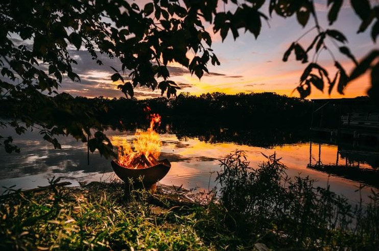 Fire pit burning at a lake at sunset