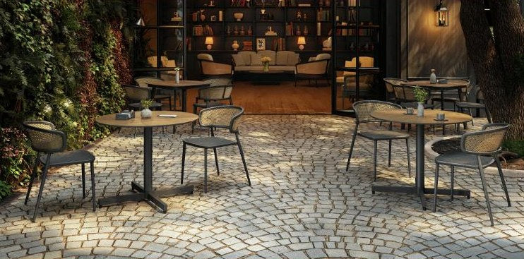 Outdoor bistro tables and chairs on a cobblestone patio at evening