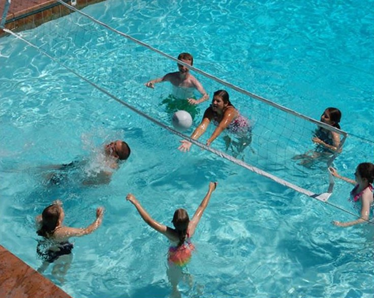 Family playing volleyball in a backyard pool