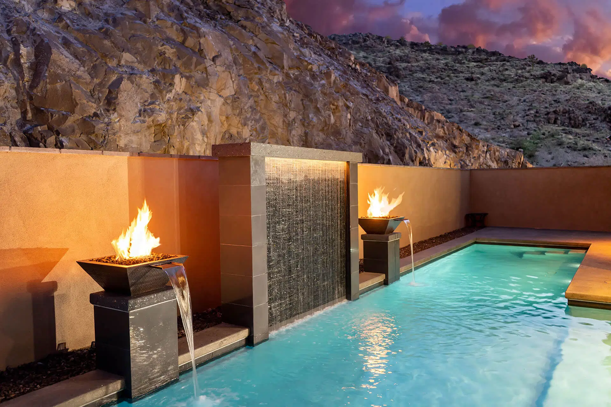 The Outdoor Plus Maya hammered copper fire and water bowl spilling beside a pool at dusk