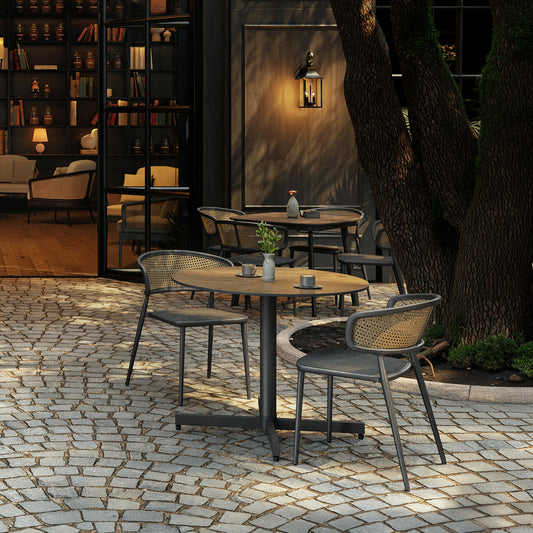 Cane weave dining chairs with padded sling seats drawn up to an outdoor dining table
