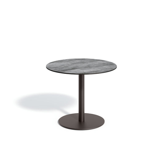 Oxford Garden Travira 36 inch round outdoor bistro table with a high pressure laminate top on a carbon black powder coated aluminum pedestal base, shown on a plain white background