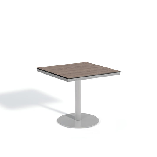 Oxford Garden Travira 38 inch square outdoor bistro table with a high pressure laminate top on a flint grey powder coated aluminum pedestal base, shown on a plain white background