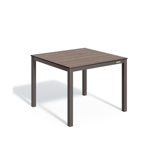Oxford Garden Travira 39 inch square outdoor dining table with a high pressure laminate top on a carbon black powder coated aluminum frame, shown on a plain white background