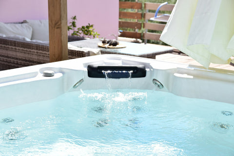 Hot tub with a waterfall spout and jets on a sunny patio