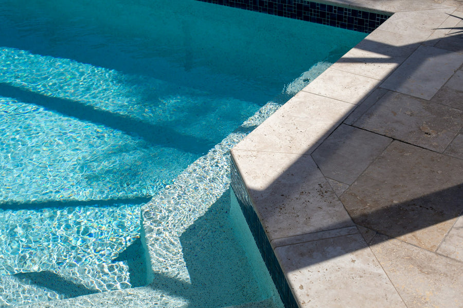 Pool steps and stone deck beside blue water