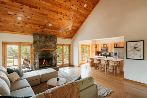 Living room with a stone fireplace burning and an open kitchen