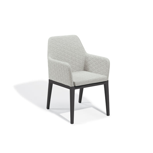 Quilted upholstered dining armchair in Canvas Granite on a Carbon powder coated aluminum frame, photographed on a plain white background